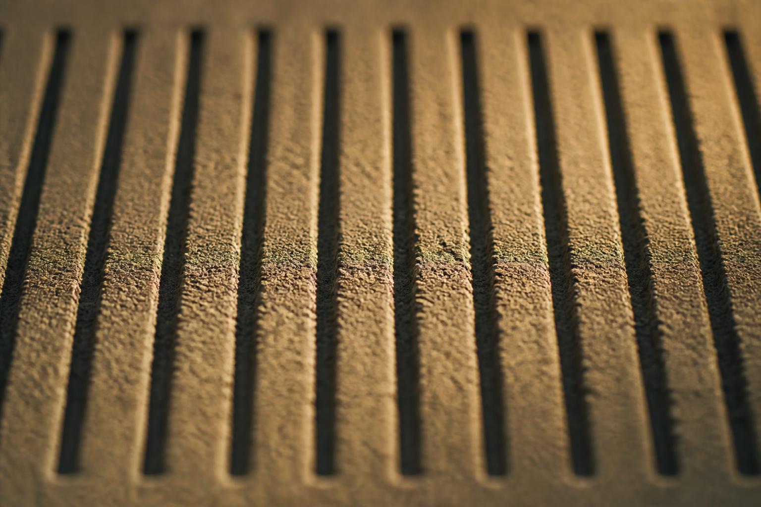 Abstract macro still life: a regular grid of fine columns pressed into a textured surface with untouched surface between them, standing in for fractional laser resurfacing.