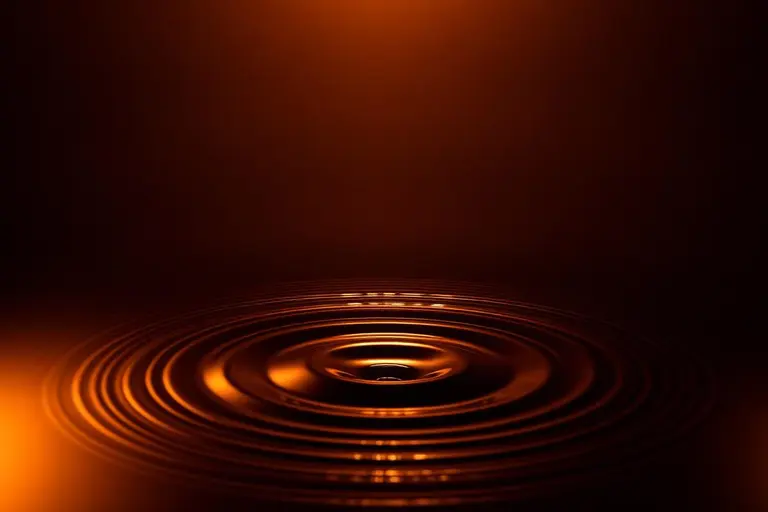Golden concentric ripples on a dark surface, representing extracorporeal shockwave therapy