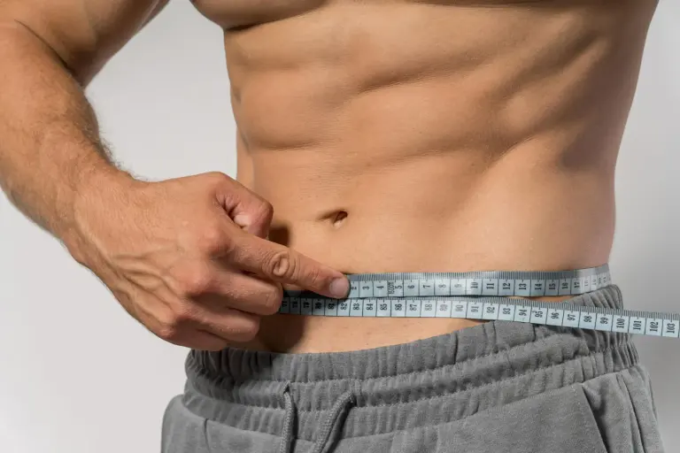 Man measuring his waist as part of a weight loss and healthspan plan